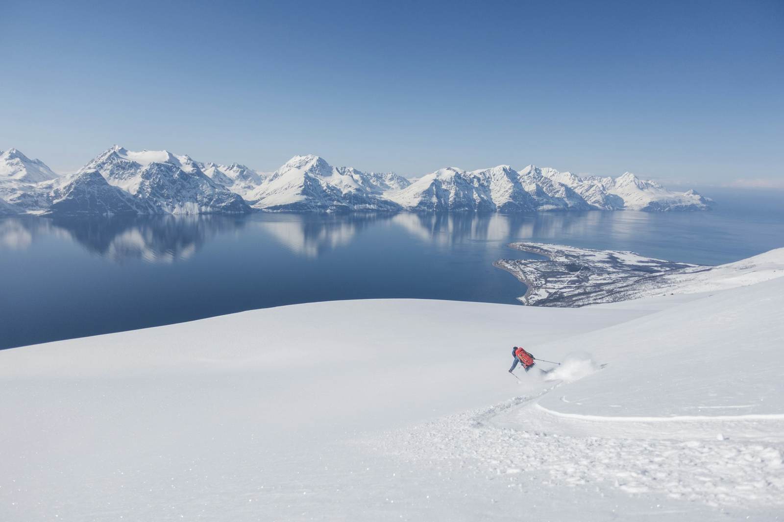 Verschneiter Hang über einem See