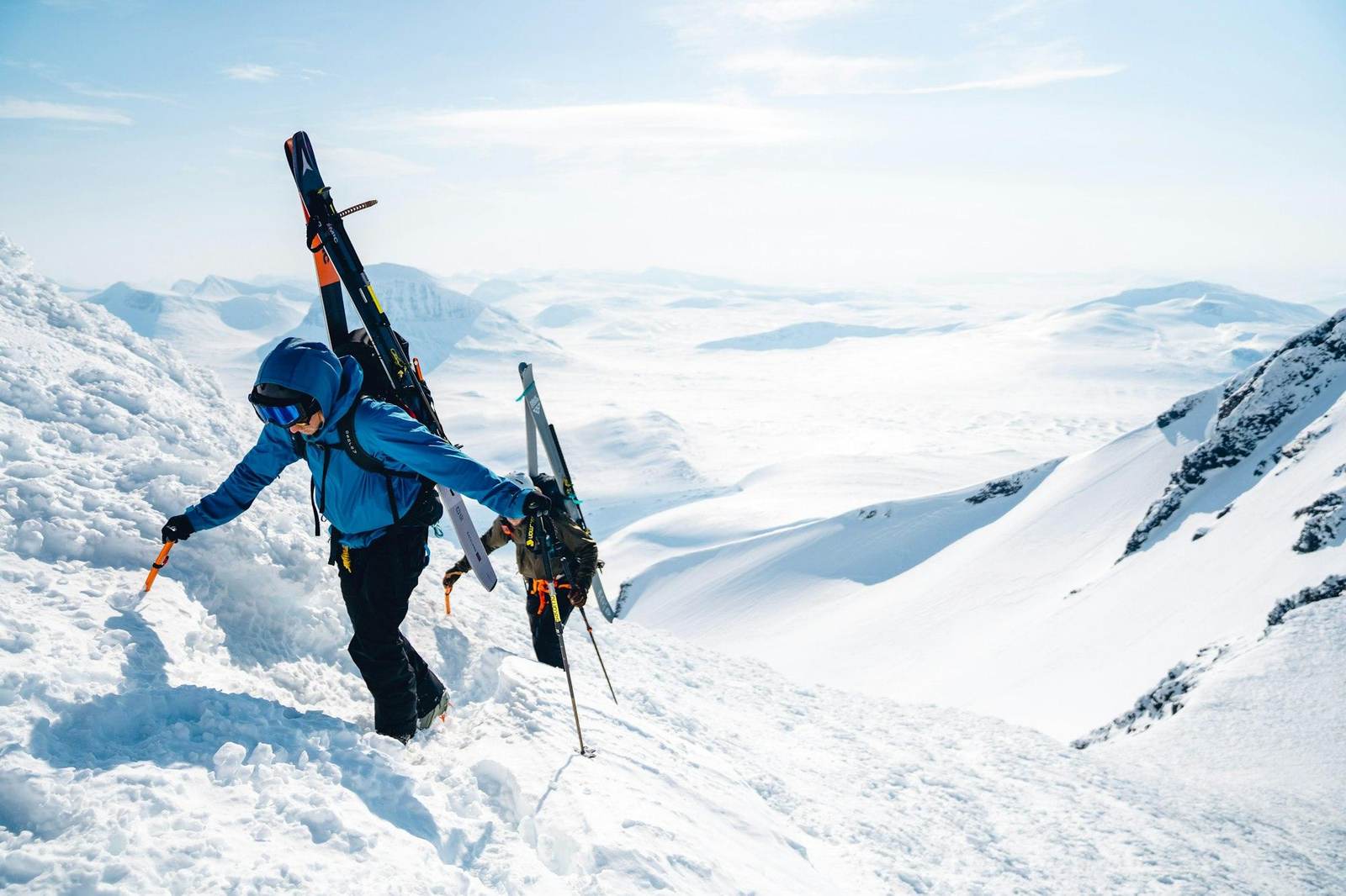 Ein Skitourengeher trägt seine Ski über einen verschneiten Grat
