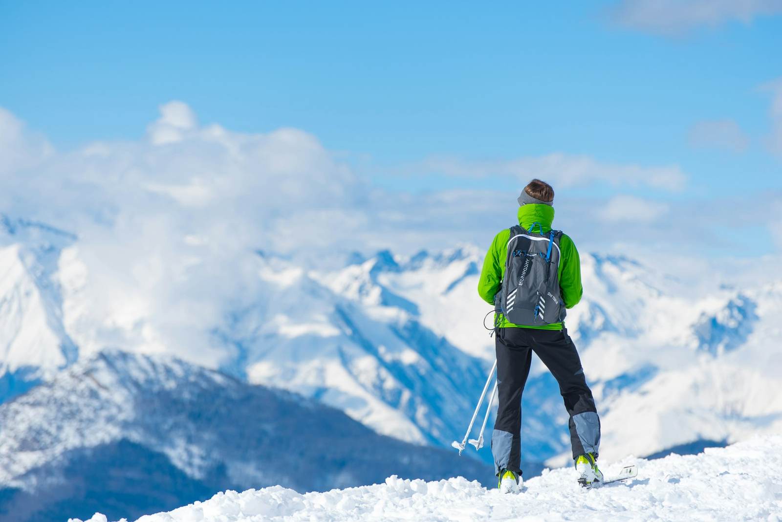 Ein Bergsteiger blickt über ein Wolkenmeer auf verschneite Gipfel