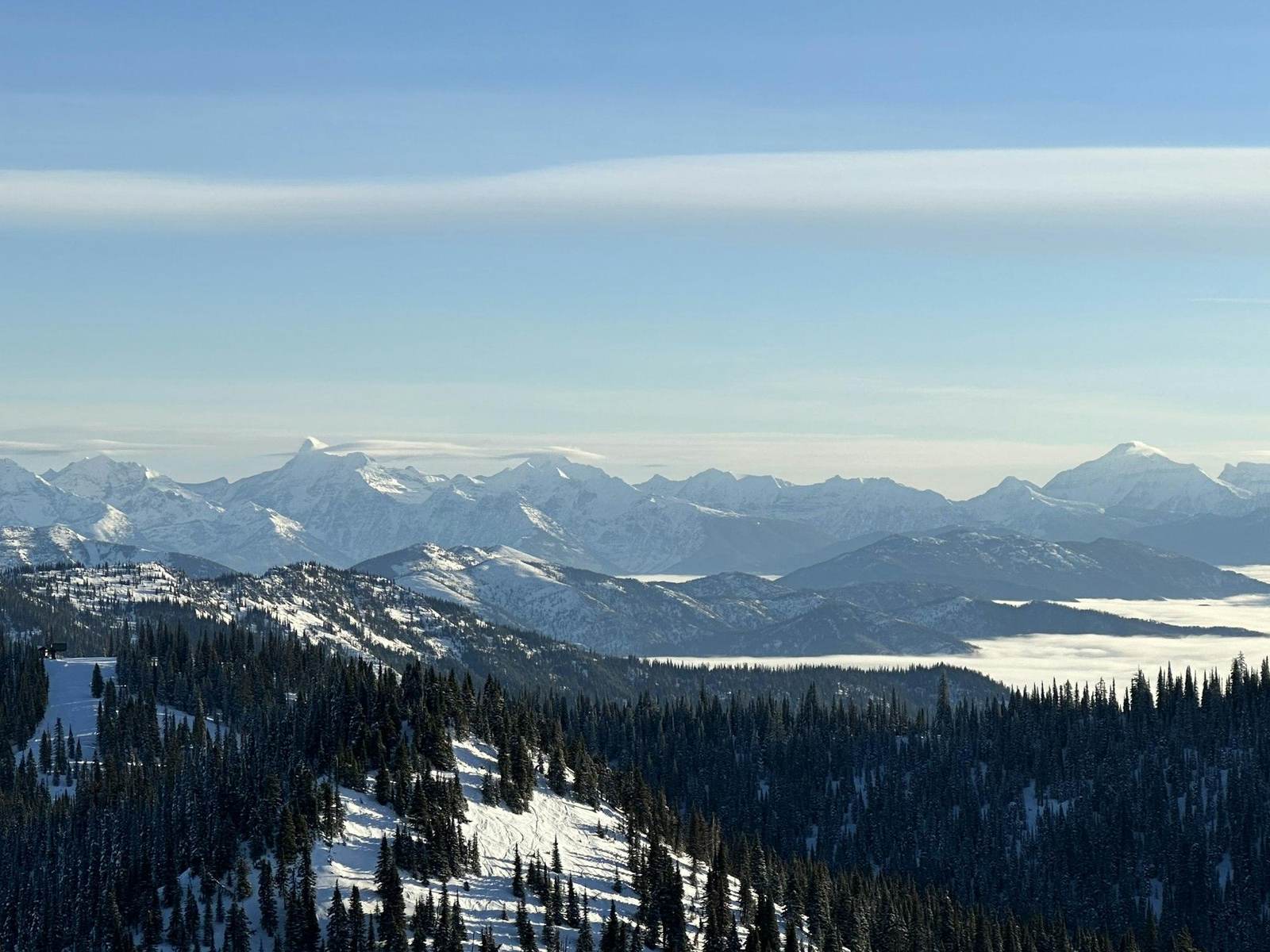 Blick vom Gipfel über verschneite Bergketten